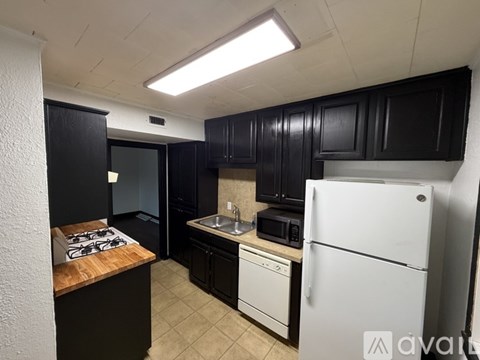 A kitchen with black cabinets and a white refrigerator.