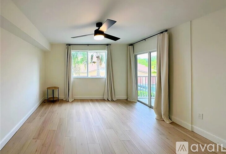 A room with a ceiling fan and sliding glass doors.