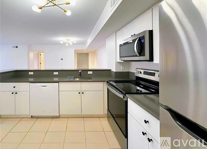 A kitchen with white cabinets and black countertops.