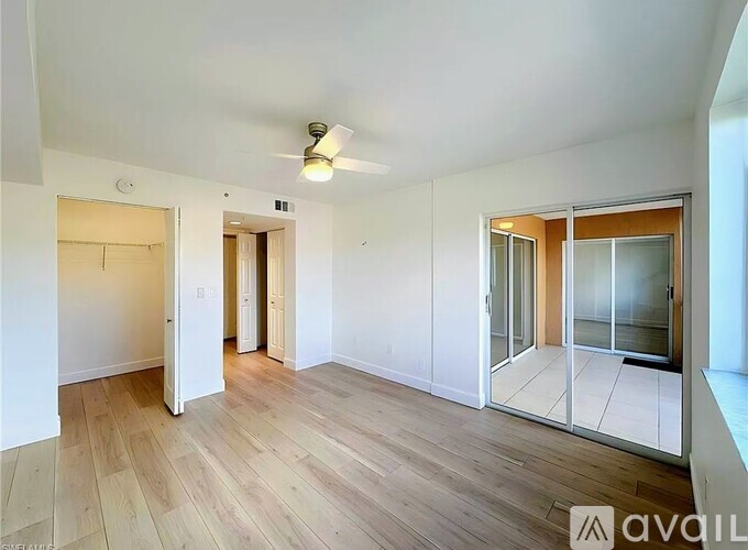 A spacious room with wooden flooring and a ceiling fan.