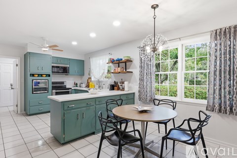 A kitchen with a table and chairs by a window.