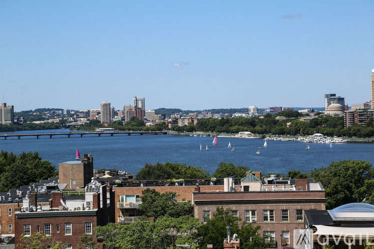 A cityscape with a river and boats in the foreground.