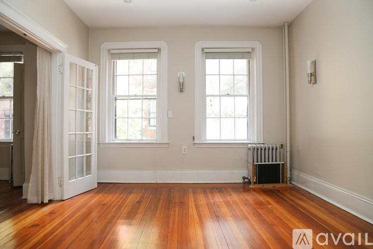 A room with wooden floors and two windows.