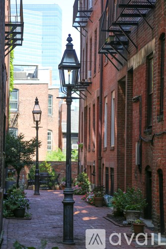 A narrow alley with brick buildings and a lamp post.