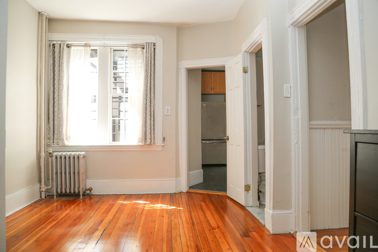 A room with wooden floors and a window with curtains.