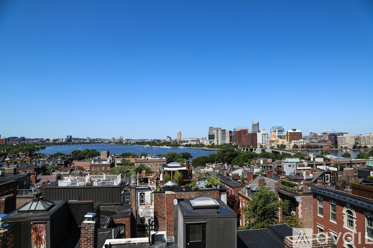A cityscape with buildings and a body of water in the distance.