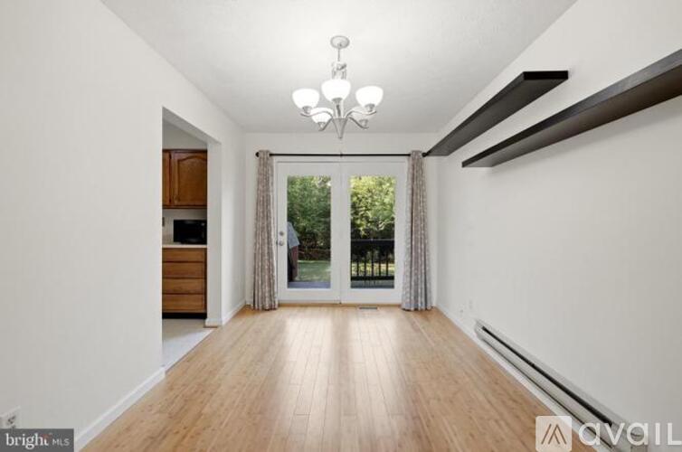 A bright and spacious room with wooden floors and a sliding glass door leading to a garden.