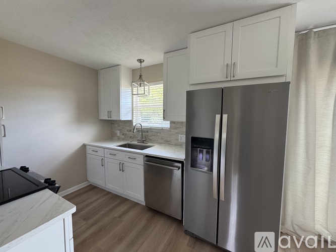A kitchen with a stainless steel refrigerator and white cabinets.