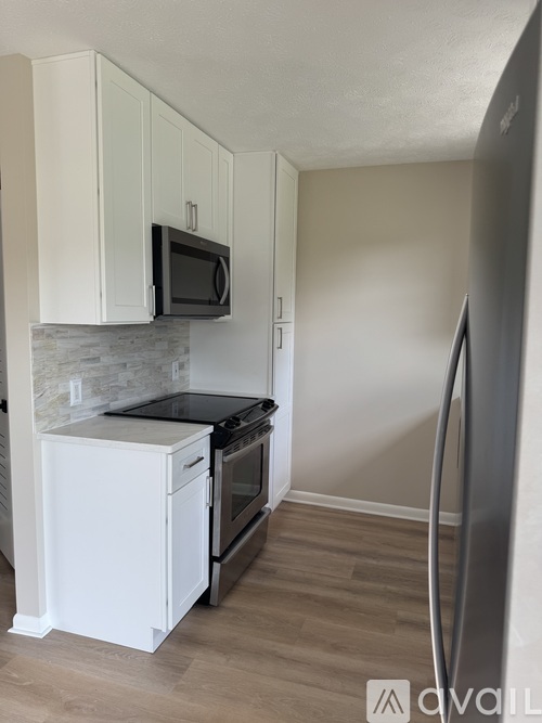 A kitchen with white cabinets and a black microwave above the stove.