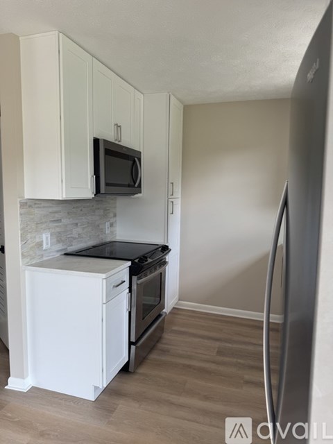 A kitchen with white cabinets and a black microwave above the stove.