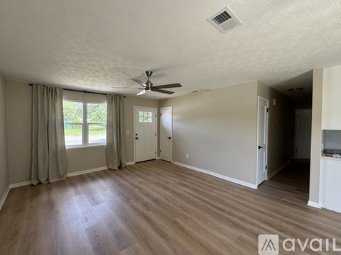 A spacious room with a ceiling fan and sliding glass doors leading to a patio.