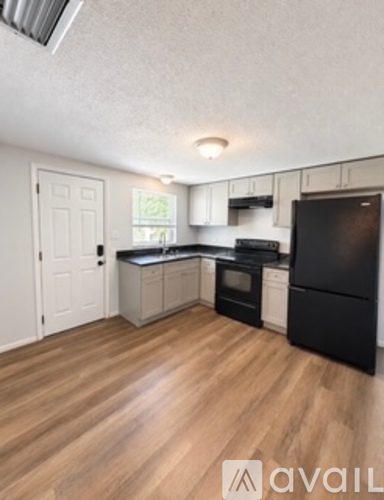 A kitchen with black appliances and wooden floors.