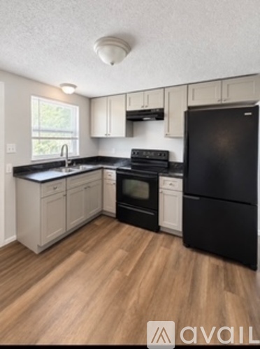 A kitchen with black appliances and wooden floors.