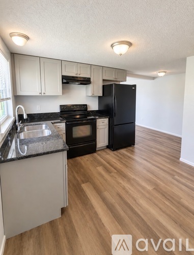 A kitchen with black appliances and wooden floors.