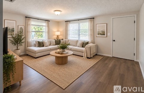 A living room with a white couch, a wooden coffee table, and a rug.