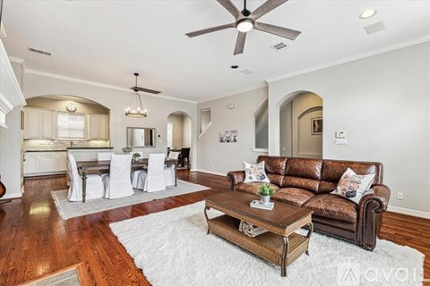 A living room with a brown couch and a white rug.