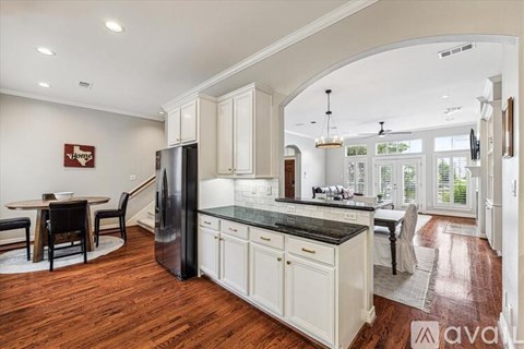 A kitchen with white cabinets and a black countertop.