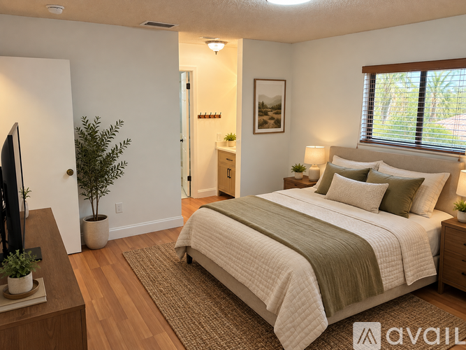 A bedroom with a bed, nightstand, and a plant.