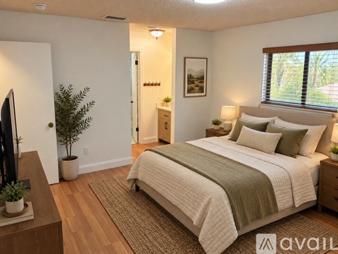 A bedroom with a bed, nightstand, and a plant.