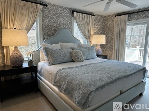 A bedroom with a large bed and two lamps.