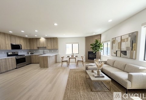 A spacious living room with a beige sofa, wooden floors, and a large painting on the wall.