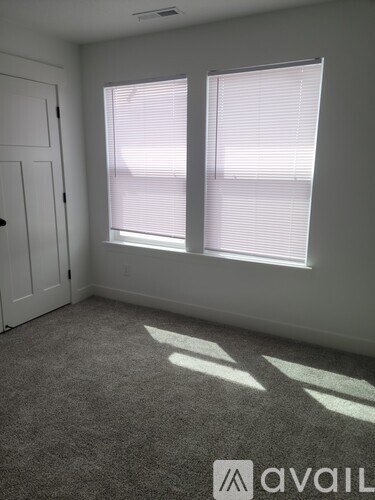 A room with a carpeted floor, a door, and a window with blinds.