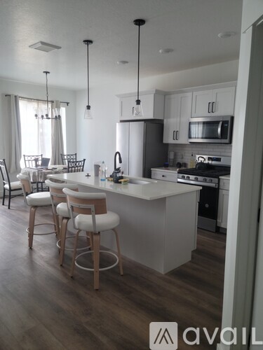 A kitchen with a white island and bar stools.