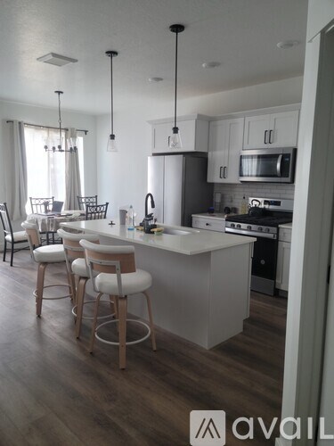 A kitchen with a white island and bar stools.