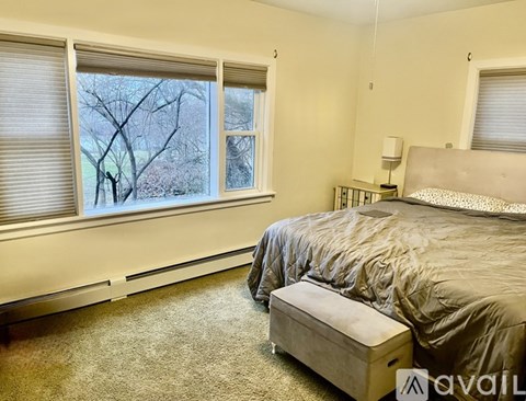 A bedroom with a large bed and a window with blinds.