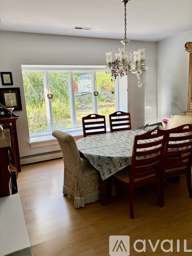 A dining room with a table set for four and a chandelier.