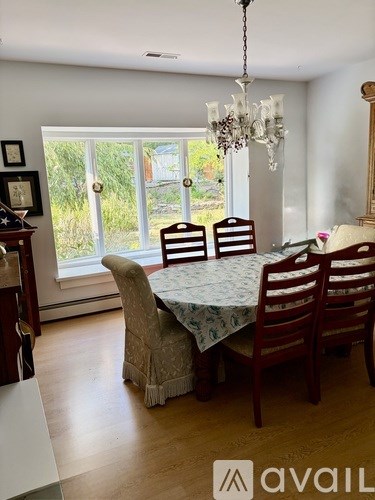 A dining room with a table set for four and a chandelier.