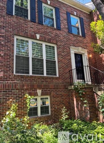 A red brick building with white windows and a balcony.