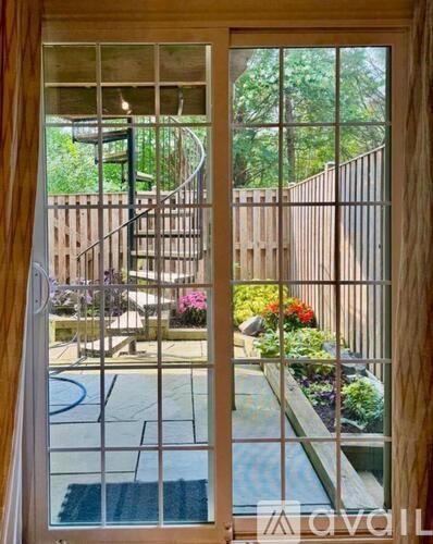 A view from inside a house looking out through a glass door to a backyard with a pool and a spiral staircase.