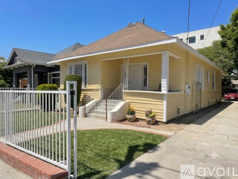 A yellow house with a white fence in front.