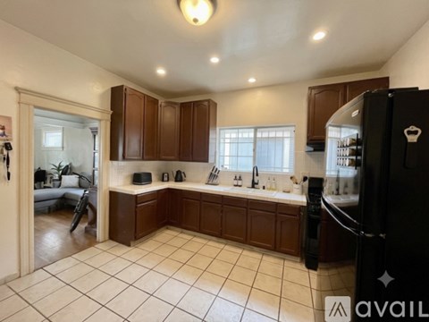 A kitchen with brown cabinets and a black refrigerator.