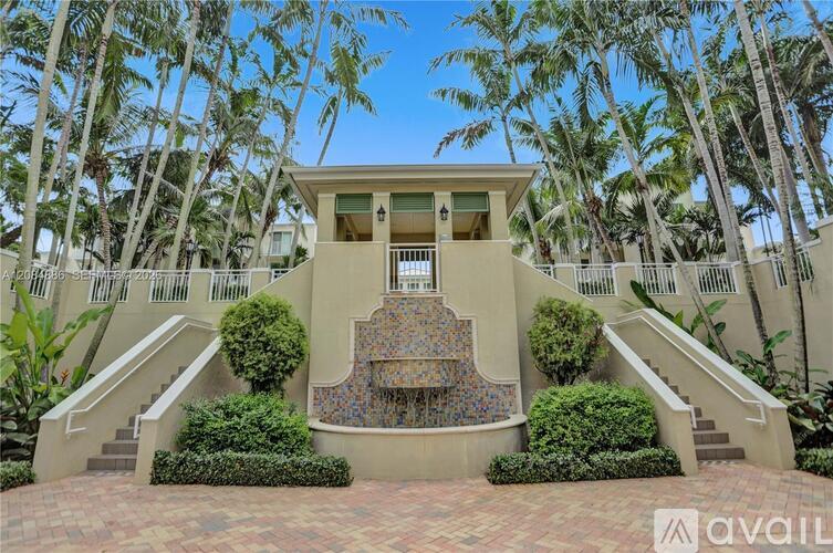A house with a staircase surrounded by greenery and palm trees.