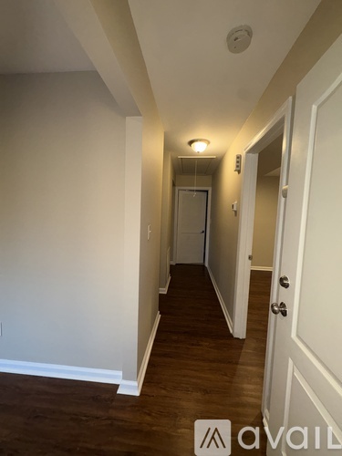 A hallway with a door at the end and a light on the wall.