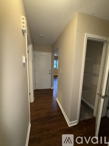 A hallway with a door on the right and a light switch on the wall.