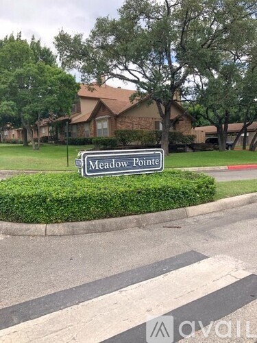 A street sign that says Meadow Pointe in front of a house.