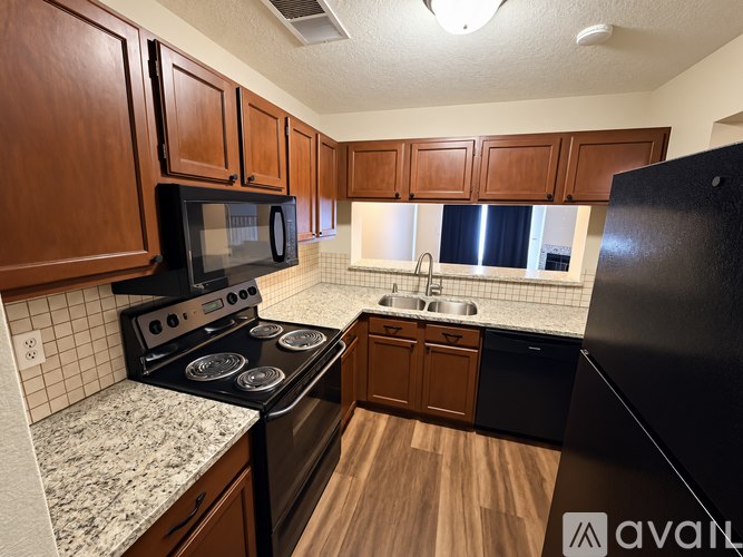 A kitchen with black appliances and wooden cabinets.