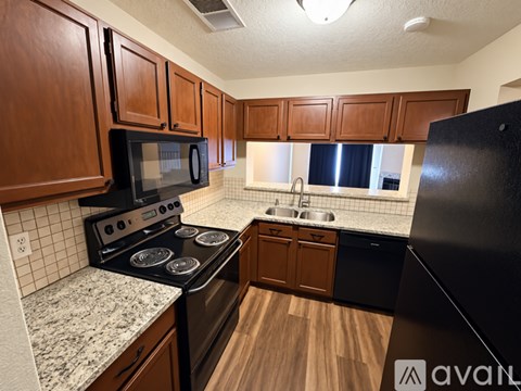 A kitchen with black appliances and wooden cabinets.