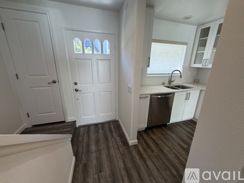 A kitchen with white cabinets and a wooden floor.