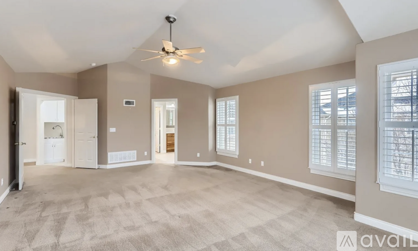 A spacious room with a ceiling fan and carpeted floor.