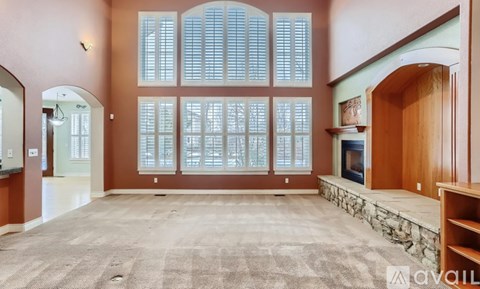 A spacious living room with a fireplace and large windows.