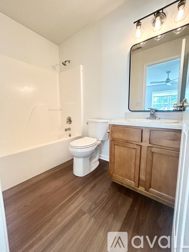 A bathroom with a toilet, sink, and mirror.