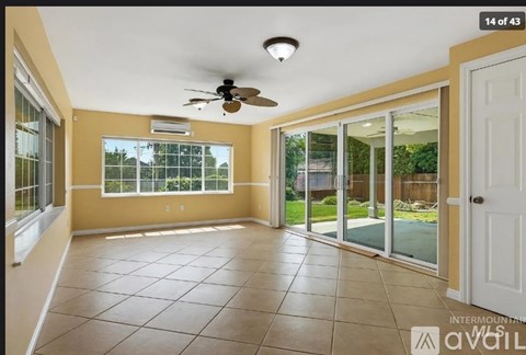 A spacious room with a ceiling fan and sliding glass doors leading to a backyard.