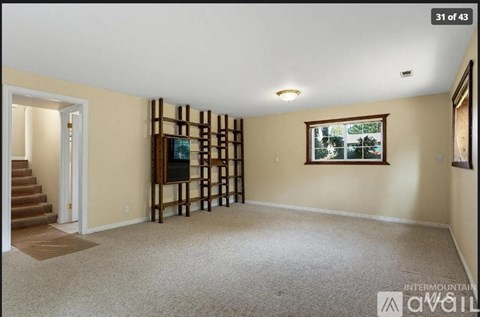 A living room with a staircase and a flat screen TV.
