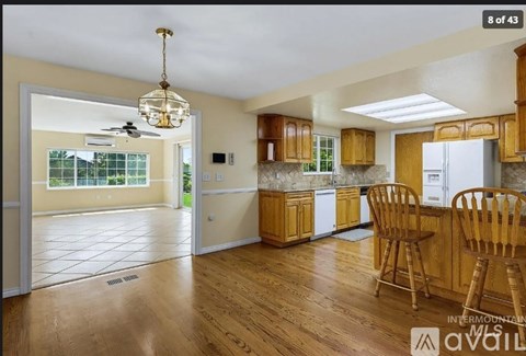 A kitchen with wooden floors and cabinets, a ceiling fan, and a dining table with chairs.