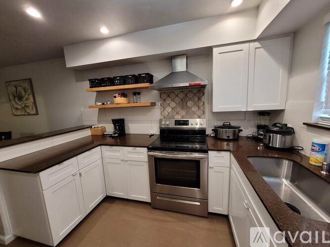 A kitchen with white cabinets and a brown countertop.