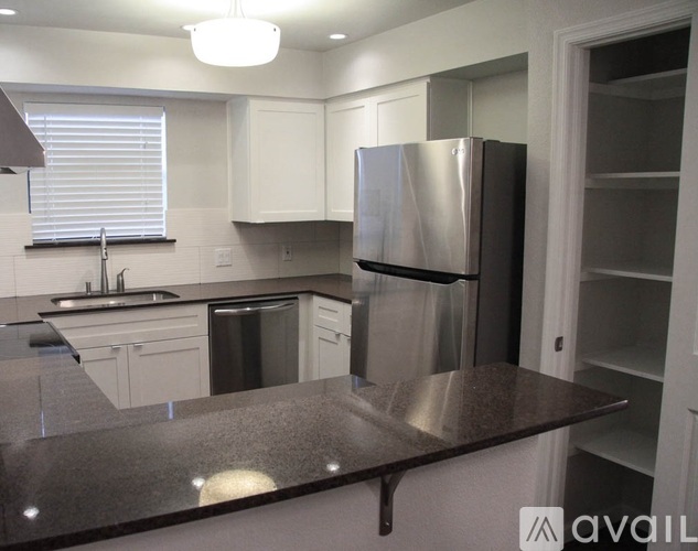 A kitchen with a stainless steel refrigerator and a granite countertop.